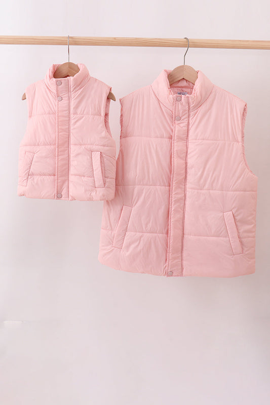Two pink puffer vests hanging on a rack against a white background